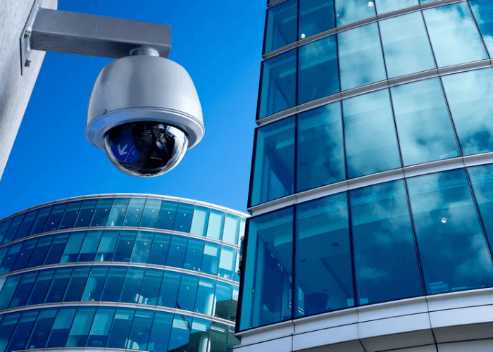 Security camera mounted near modern glass office buildings.