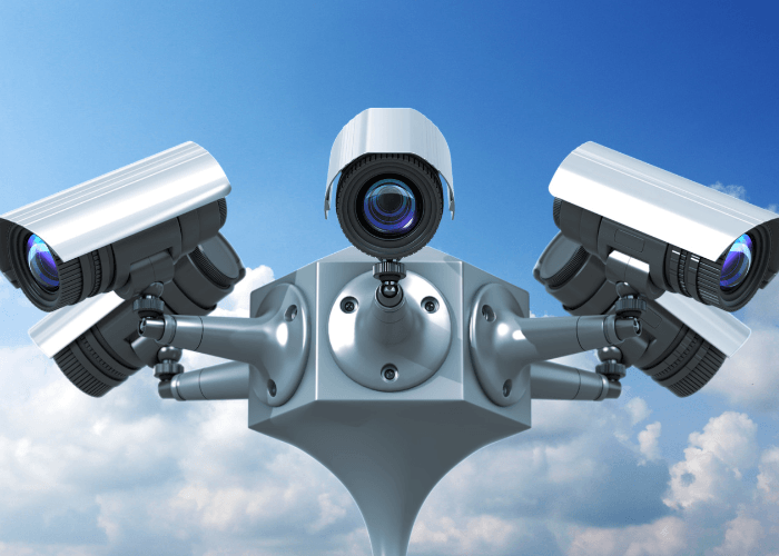 A futuristic security robot with multiple surveillance cameras against a blue sky.